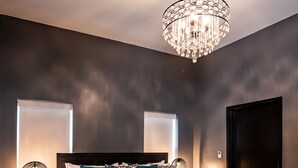 A modern bedroom with a large bed, dark walls, and a chandelier. - Duets Bed & Breakfast (Tulsa)