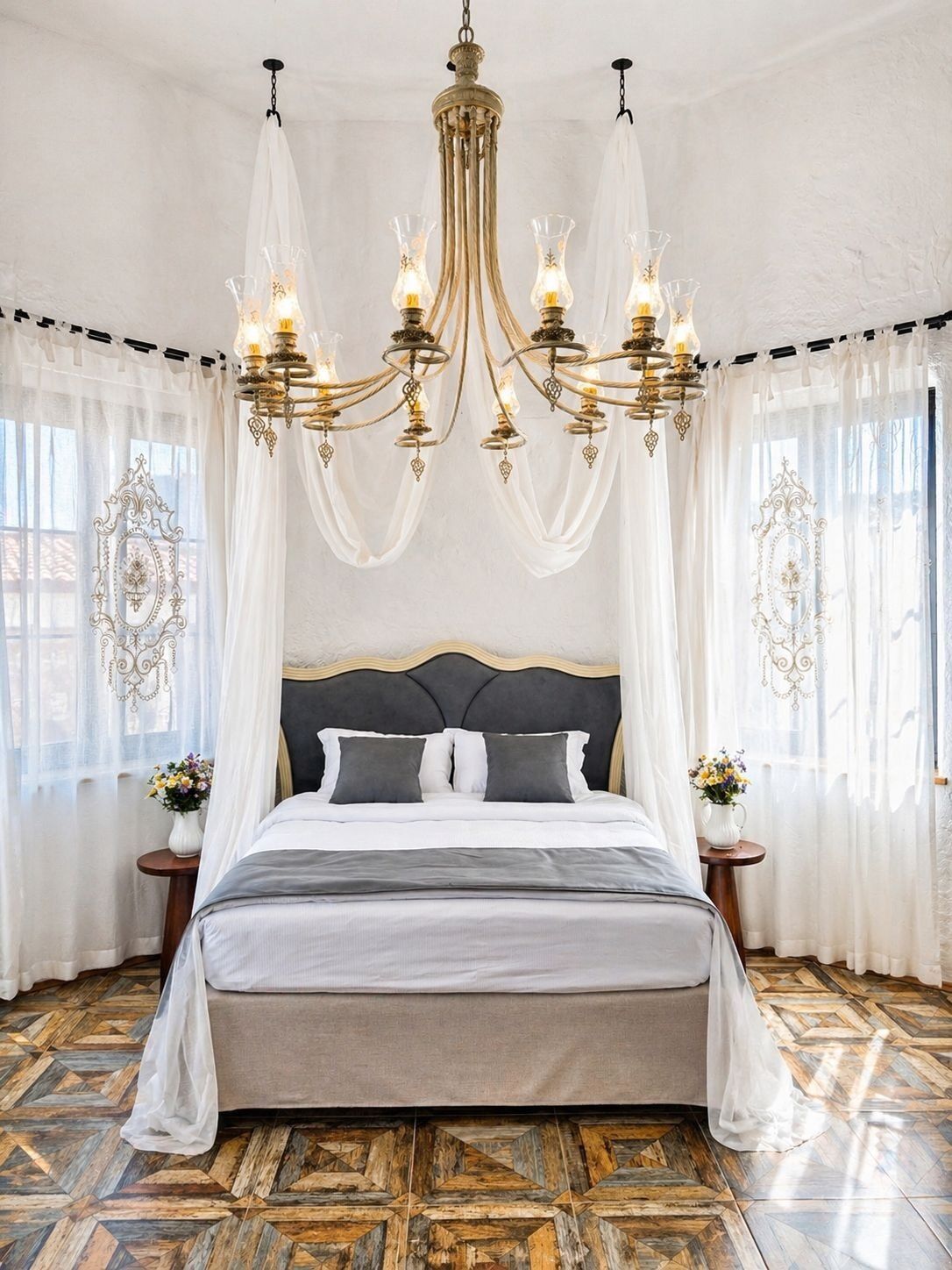 A bedroom with a large bed, a chandelier, and a herringbone-patterned floor.