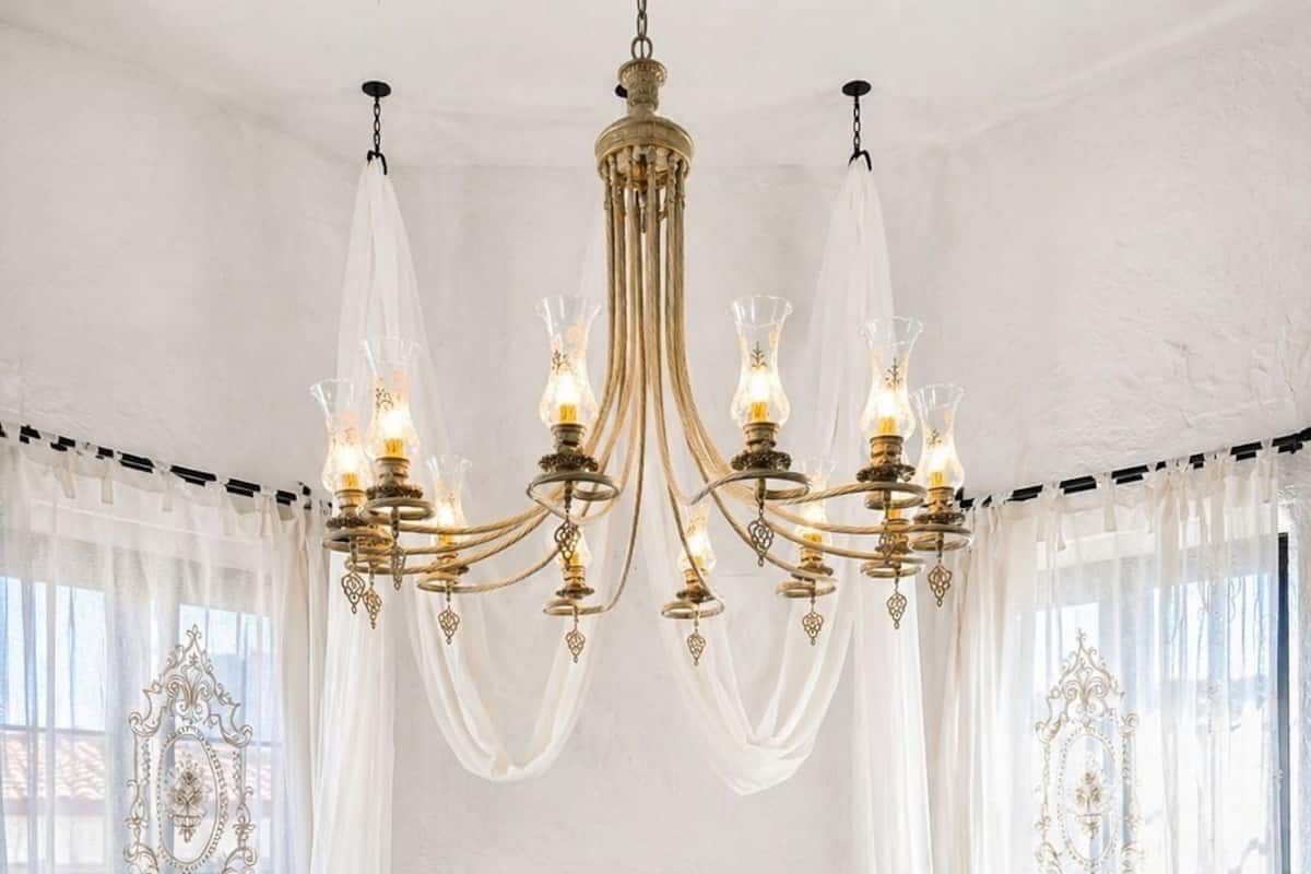 A bedroom with a large bed, a chandelier, and a herringbone-patterned floor.