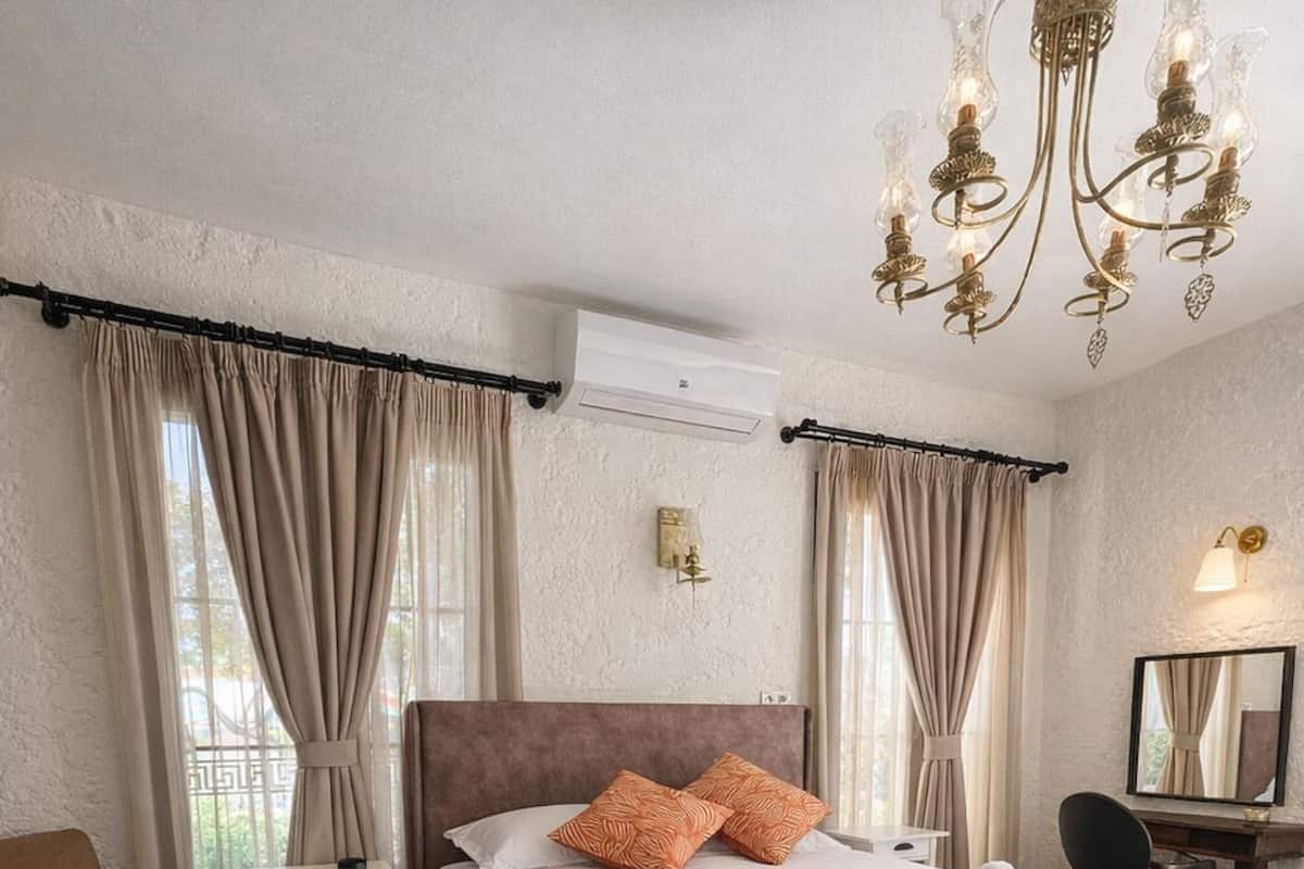 A hotel room with a large bed, a bedside table, a chair, a desk, and a chandelier.