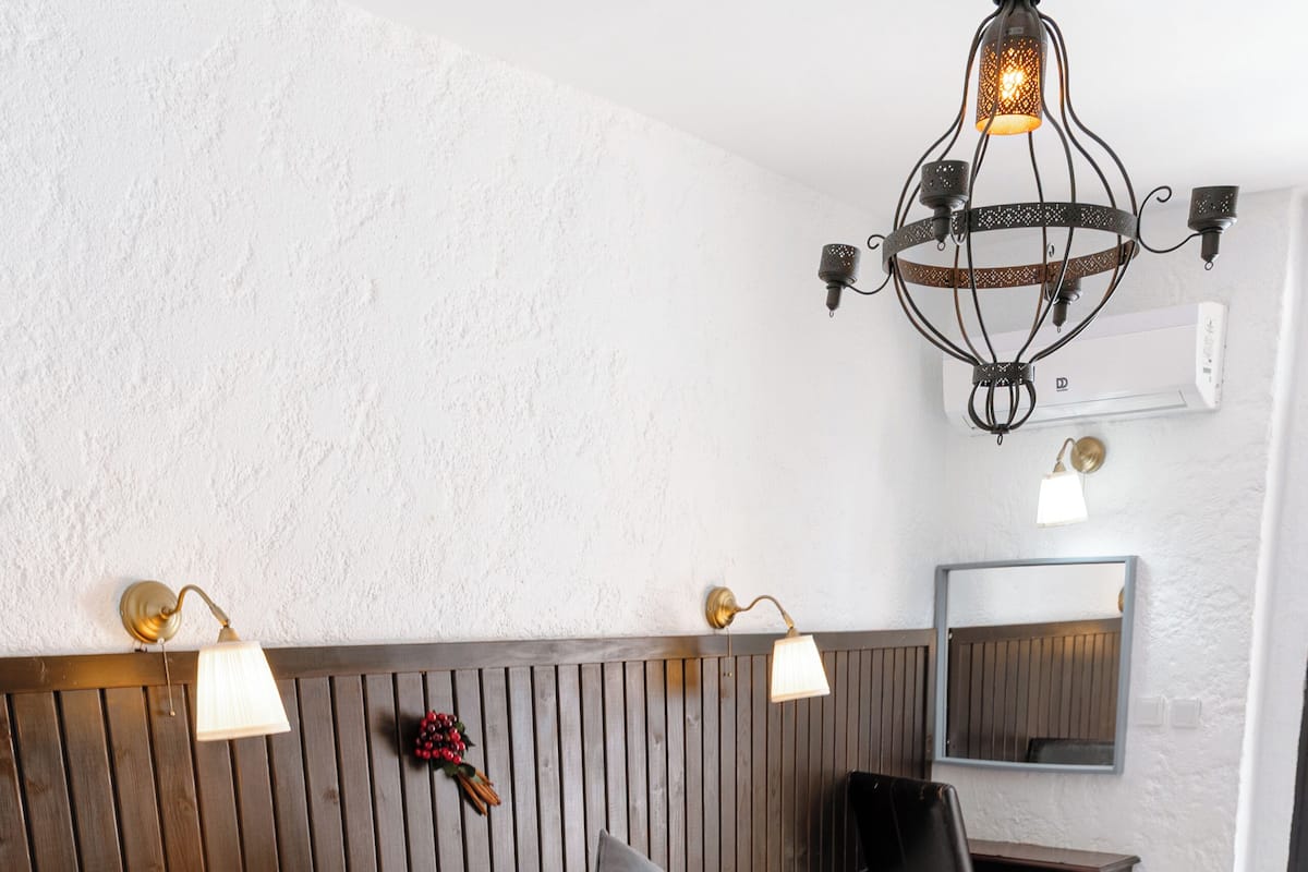 A hotel room with two beds, a desk, a chair, a mirror, and a chandelier.