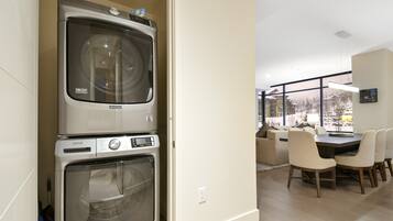 A modern kitchen with a double oven, a dining area with a table and chairs, and a view of a snowy landscape through large windows.