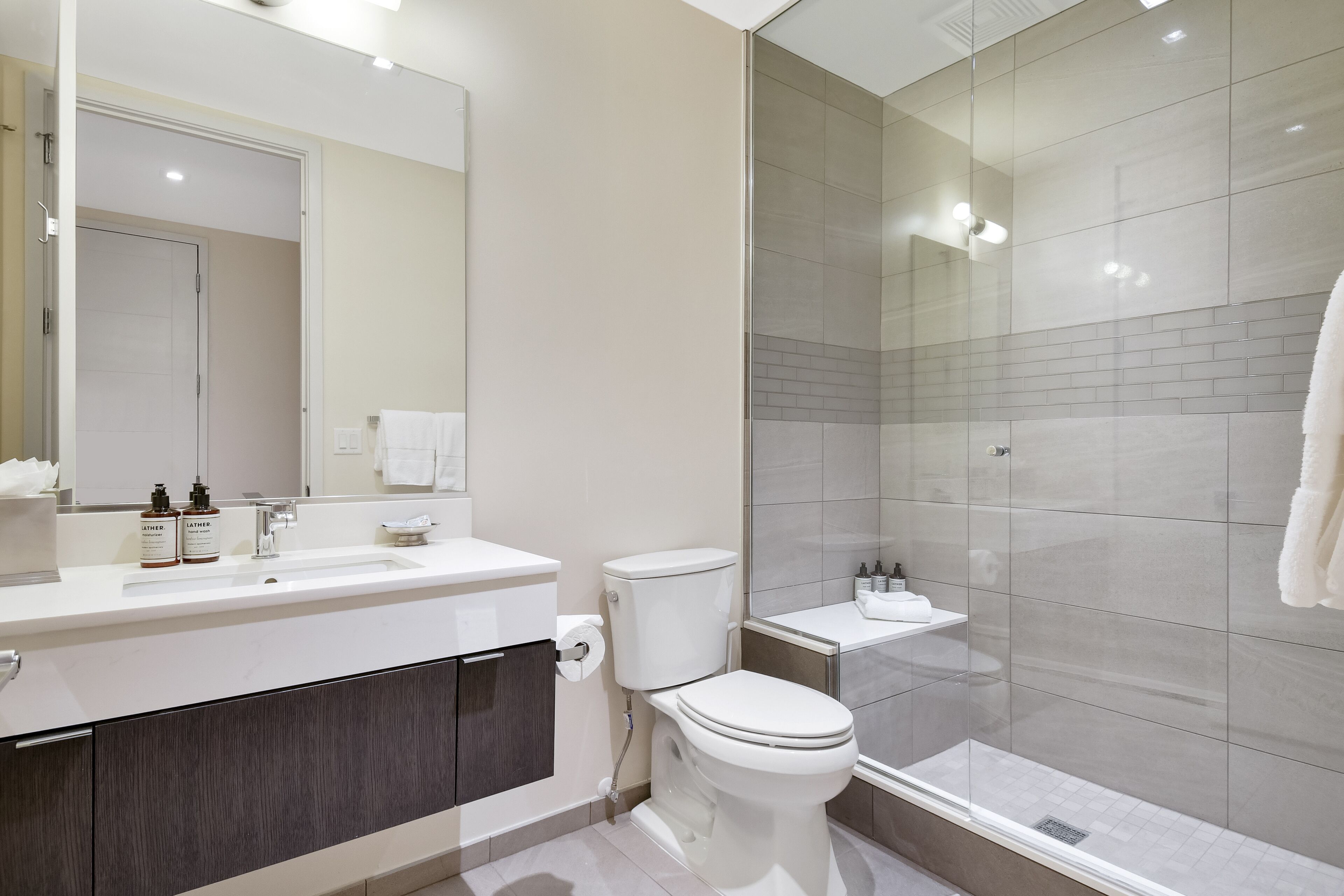 Un bagno moderno con cabina doccia in vetro, lavabo bianco e water.
