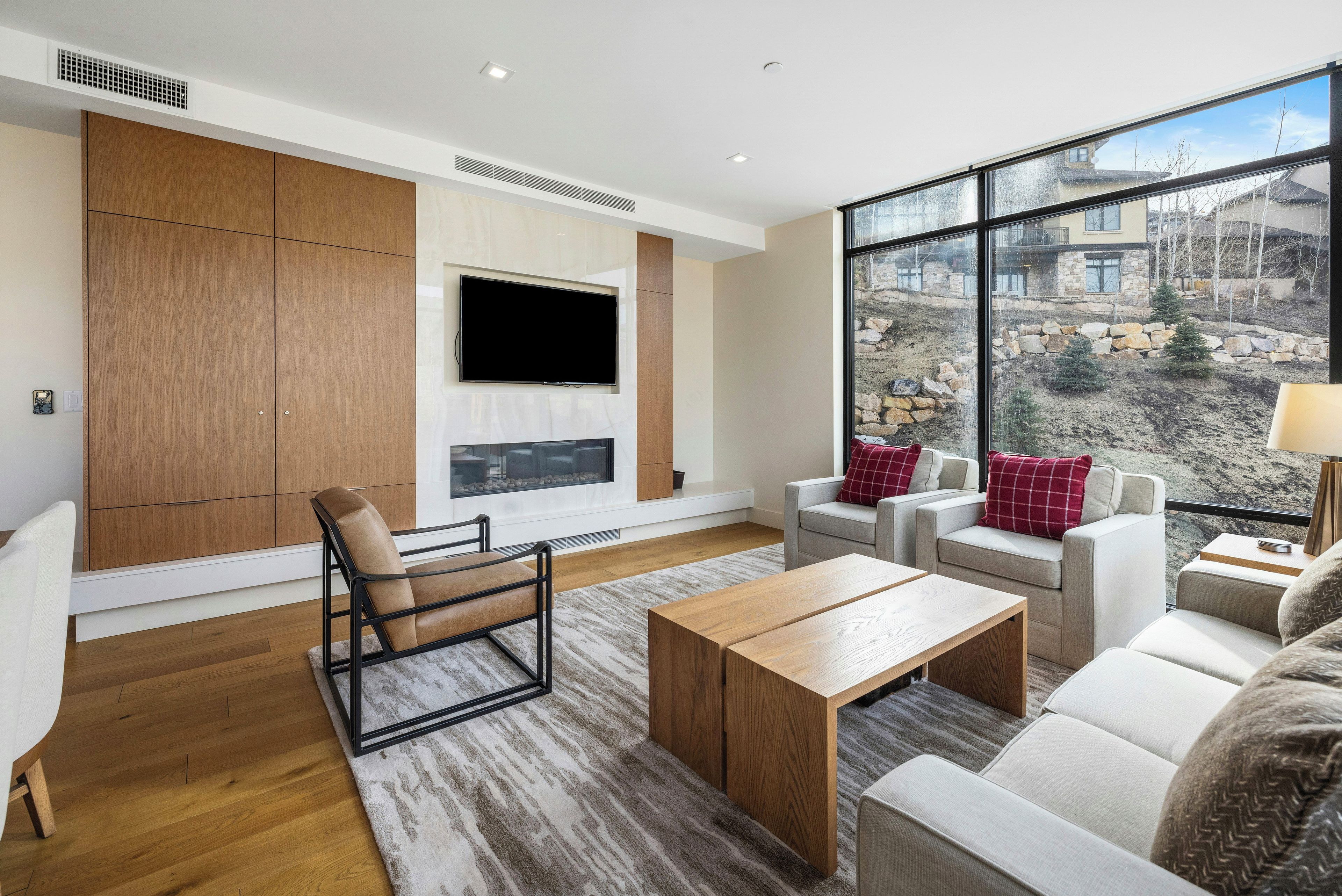 Ein modernes Wohnzimmer mit großem Fenster, einem Flachbildfernseher und einer Sitzecke mit Sofas und einem Couchtisch.