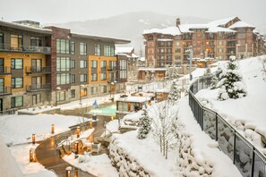 Un resort cubierto de nieve con edificios modernos, una zona de piscina y un paisaje nevado.