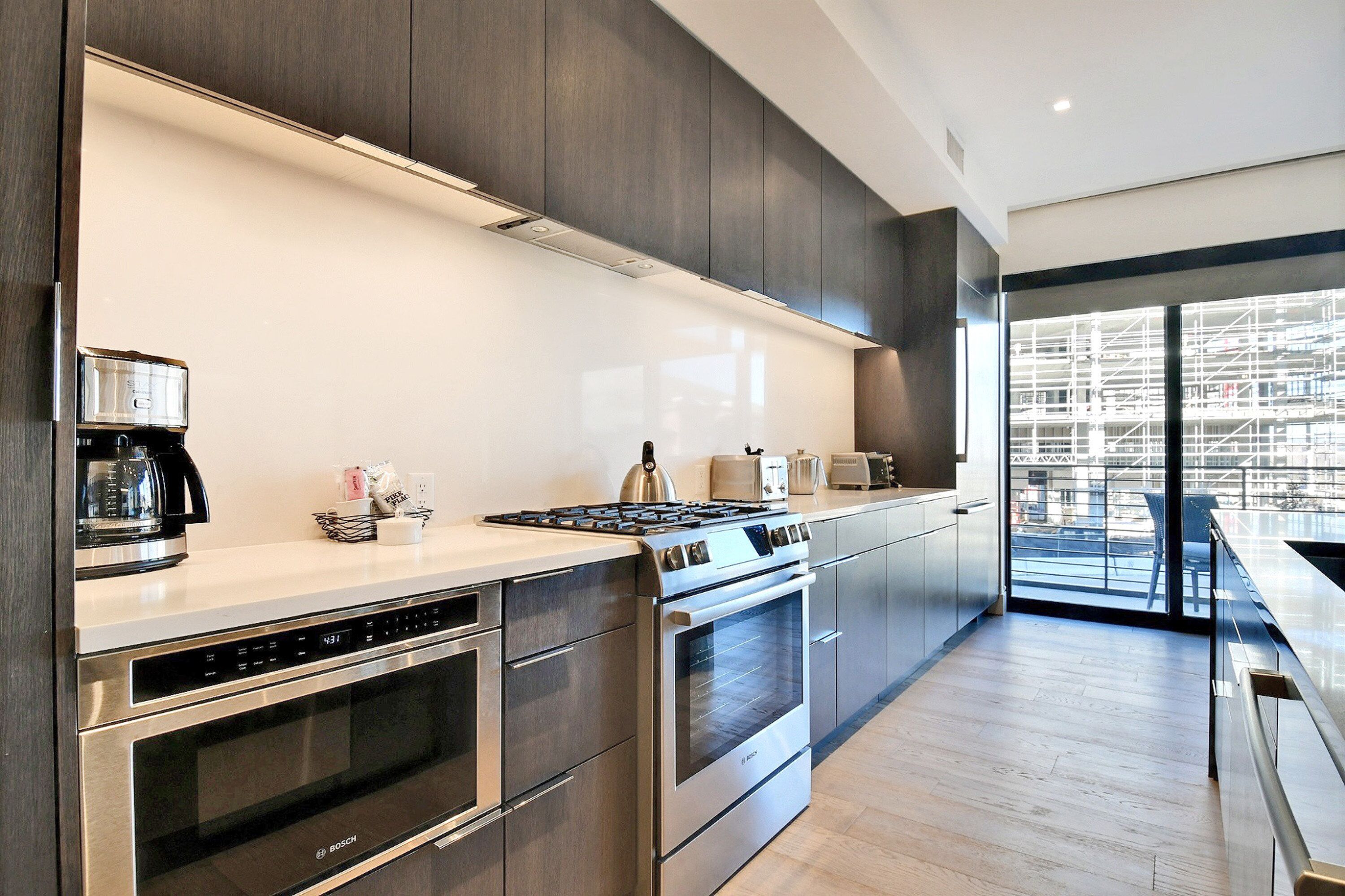 A modern kitchen with stainless steel appliances, a large window, and a view of the cityscape.