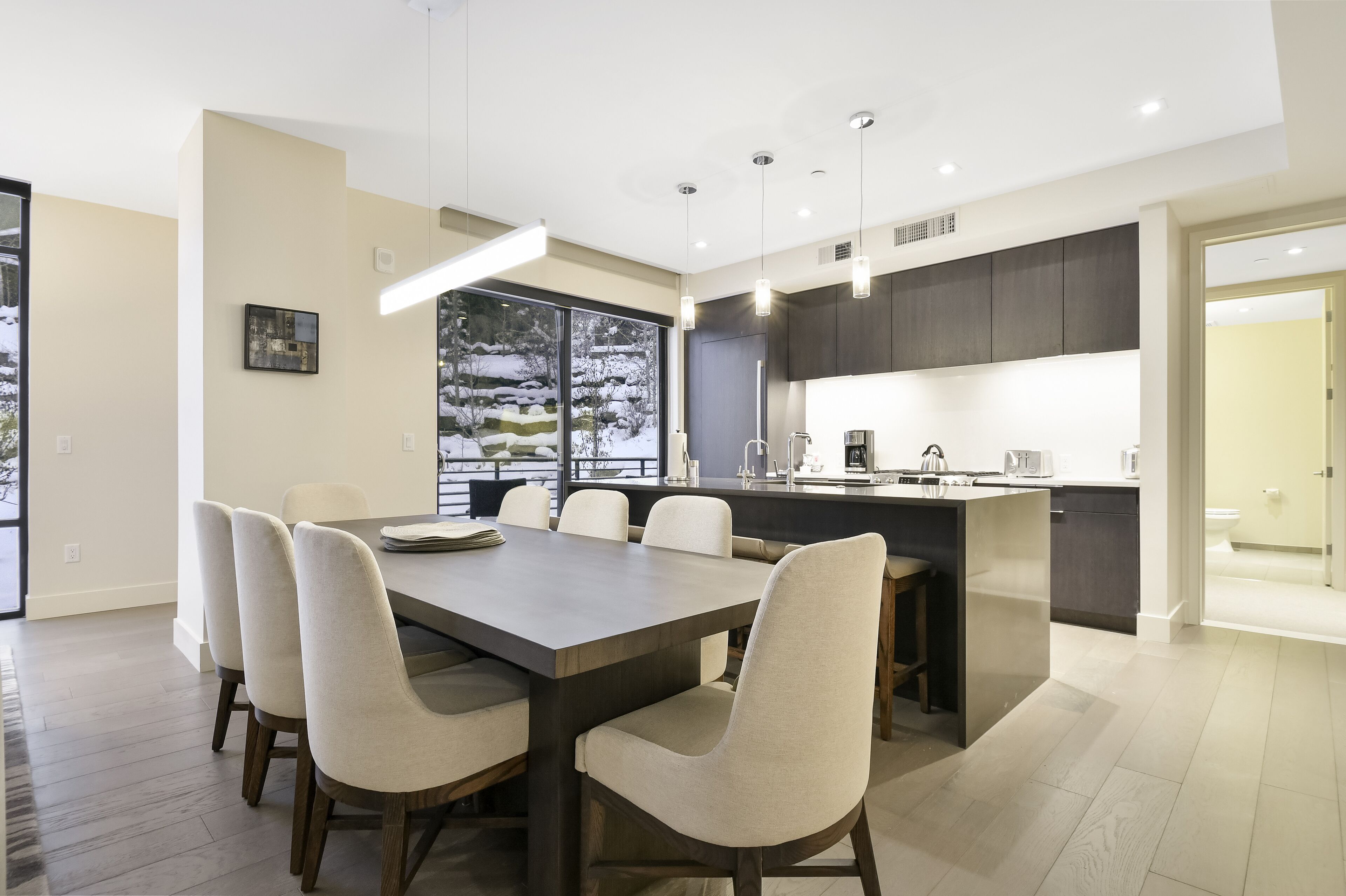 A modern kitchen with a central island, dark cabinetry, and pendant lighting.