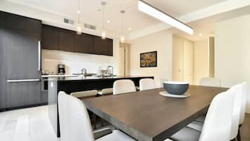 A modern kitchen with dark cabinets, a central island, and a dining area with a large table and chairs.