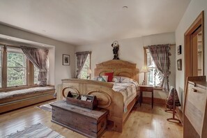 A bedroom with a wooden bed, a bench, a bedside table, a dresser, and a window with curtains. - Saddleridge (Avon)