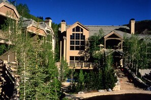 A resort with multiple buildings, a central structure with large windows, and a staircase leading to a lower level. - Saddleridge (Avon)