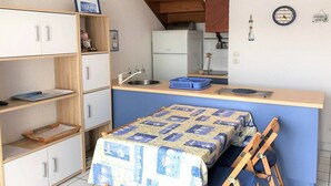 A compact room with a bed, a small kitchenette, and a wooden loft above the bed. - Cozy Apt with Terrace, 100m from St-Guirec Beach - Ploumanac'h (Perros-Guirec)