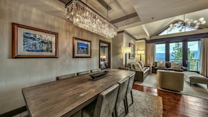 Amplia sala de estar con mesa de comedor de madera, asientos cómodos y ventanas grandes con vistas al exterior.