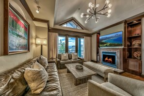 A spacious living room with a leather sofa, a coffee table, and a fireplace. - Constellation Residences (Truckee)
