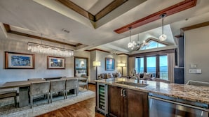 Una cocina moderna con una isla grande, suelo de madera y un comedor con mesa y sillas.