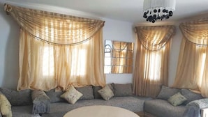 A living room with a sofa, a round table, and curtains. - Residence Sogator 2382 (Saidia)