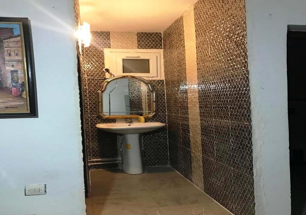 Un baño con lavamanos, espejo y paredes con azulejos.