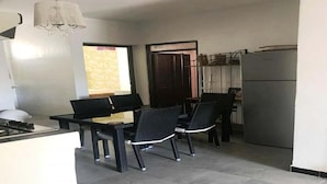 A compact kitchen with a dining area, featuring a refrigerator, a sink, and a chandelier. - Residence Sogator 2382 (Saidia)