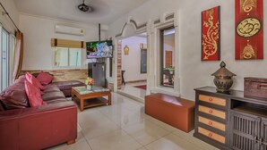 A modern living room with a red sofa, a coffee table, and a television. There is a decorative Buddha head and a red and gold artwork on the wall. - Villa 6 bedrooms near Walking Street & beach ★★★★★ (Pattaya)