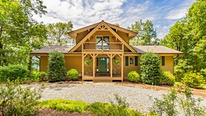 A two-story house with a front porch, a balcony, and a stone foundation. - Mountain Lure: VIEWS OF BLUE RIDGE MTNS & LAKE LURE - NEAR ASHEVILLE & BLACK MTN (Old Fort)