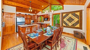 A spacious kitchen with wooden cabinets, a central island, and a dining area with a large rug. - Mountain Lure: VIEWS OF BLUE RIDGE MTNS & LAKE LURE - NEAR ASHEVILLE & BLACK MTN (Old Fort)