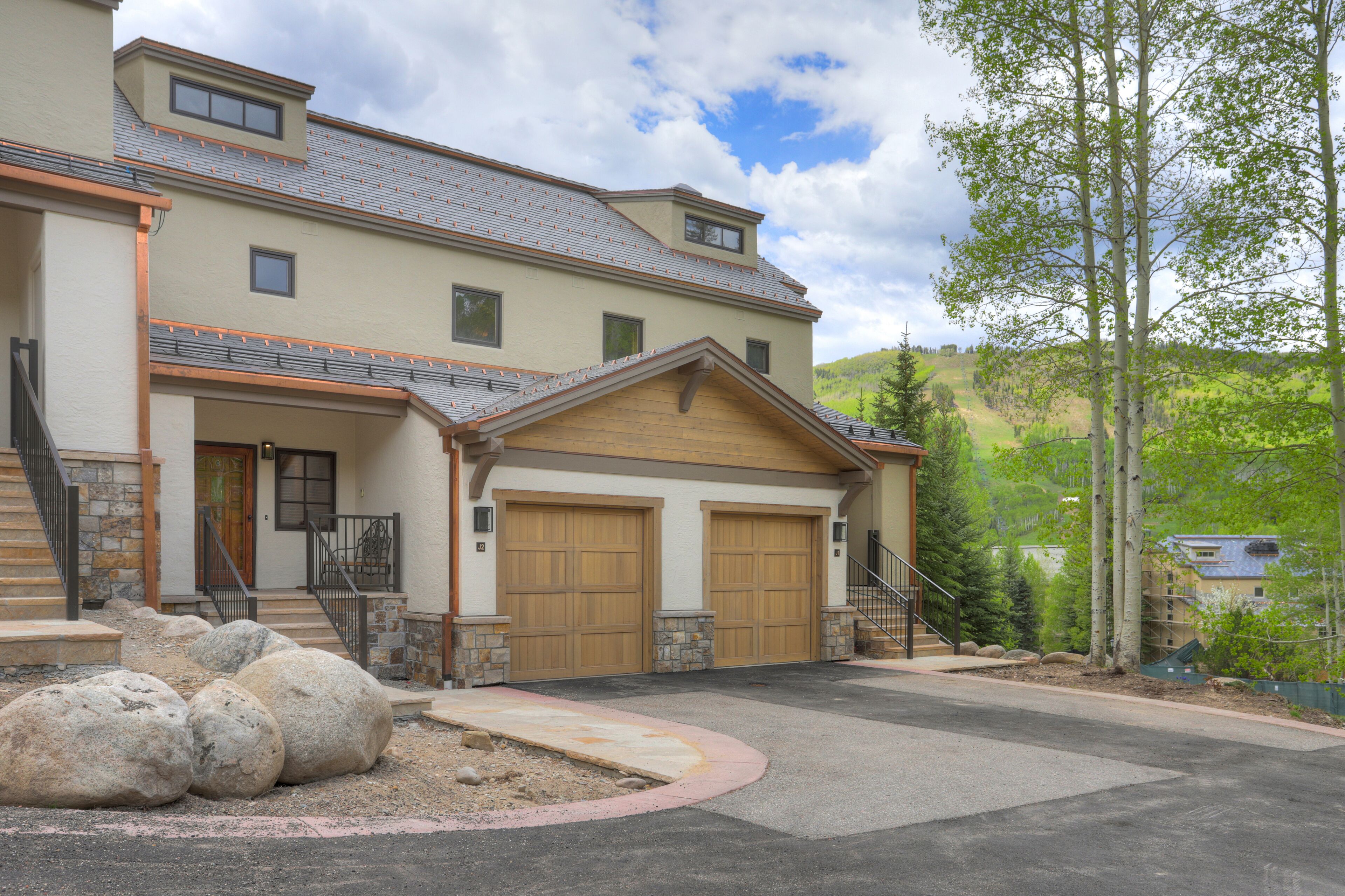 A two-story house with a garage, stone steps, and a landscaped driveway.