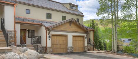 A two-story house with a garage, stone steps, and a landscaped driveway.