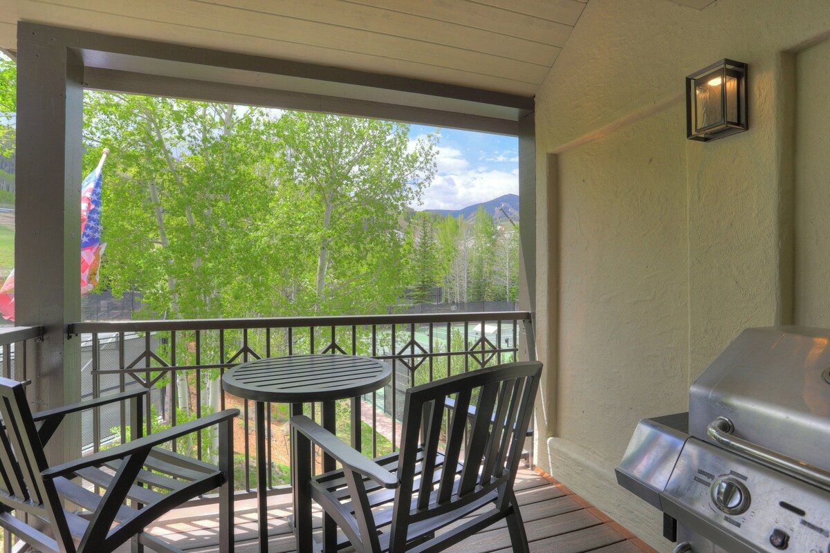 A covered outdoor area with a grill, a table, and two chairs.