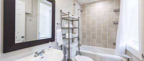 Ein Badezimmer mit weißem Waschbecken, Toilette und Duschbereich.