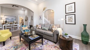Un saló modern amb un sofà, taula de centre i butaca groga. Hi ha una escala al fons que condueix a un altre pis.