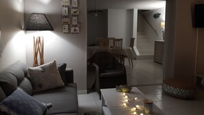Ein Wohnzimmer mit einer Couch, einem Couchtisch mit Beleuchtung und einer Wand mit gerahmten Bildern.
