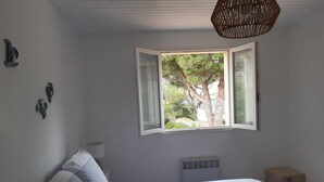 Ein Schlafzimmer mit Bett, Fenster mit freier Aussicht, Nachttisch und Wandheizung.