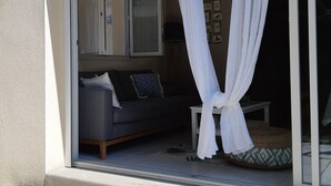 Ein Zimmer mit einer Schiebetür aus Glas, einem grauen Sofa und einem weißen Vorhang.