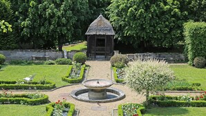 Un jardín con un pabellón, una fuente y setos bien cuidados.