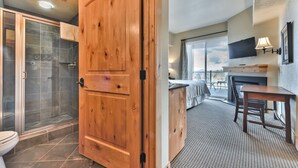 A hotel room with a wooden door, a shower, a bed, a TV, a balcony, and a dining area. - Resort property, corner one bedroom, pool, steps to skiing and golf, enjoy SV413B/C (Park City)