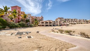 Ein Strandhotel mit mehreren Gebäuden, Palmen und einem Sandstrand.