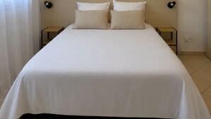 En pænt redt seng på et hotelværelse med knægt, to sengeborde og en loftlampe.