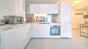 A modern kitchen with white cabinetry, a built-in oven, and a microwave.