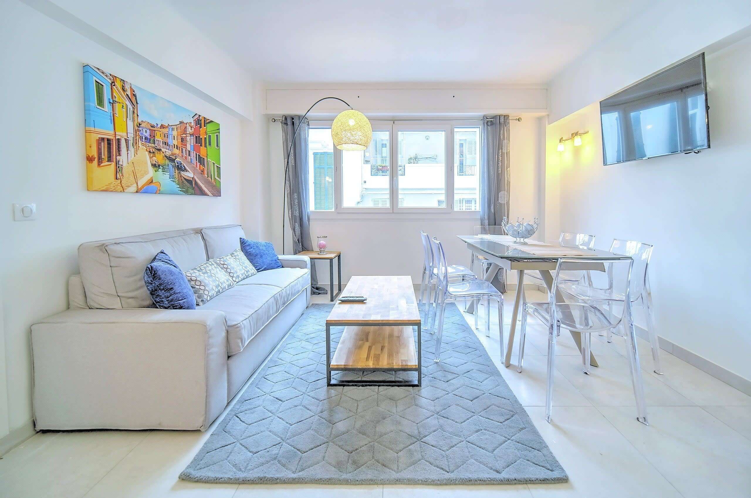 A modern living room with a sofa, a coffee table, and a dining area with chairs and a table.