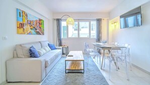 A modern living room with a sofa, a coffee table, and a dining area with chairs and a table.