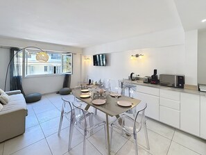 A modern kitchen with a dining area, clear chairs, a sofa, and a TV mounted on the wall. - Modern bright 3 BR 2019 refurb Croisette 1 mn, Heart Cannes Olam Properties (Cannes)