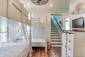 Une pièce avec des lits superposés, un escalier, une télévision et une petite table.