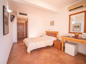 Un dormitorio con cama, mesita de noche, lámpara y un refrigerador pequeño.