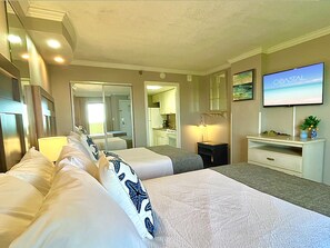 A hotel room with two beds, a TV, a desk, a mirror, and a view of the ocean. - Flawless Direct Oceanfront Suite @ The Caravelle (Myrtle Beach)