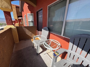 Ein Balkon mit zwei weißen Stühlen, einem kleinen Tisch und einer Tür mit der Nummer 2124.