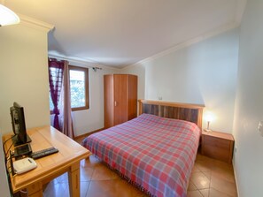 Cozy bedroom with a comfortable bed, nightstand, and desk for work and relaxation.