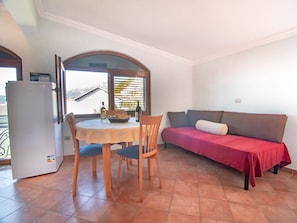 A compact living space with a dining table, chairs, a sofa, and a refrigerator. - Levantin Inn half, 1 Apt N15, Sveti Stefan, Montenegro (Budva Municipality)