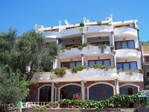 Stunning multi-story building with lush greenery-adorned balconies and arched doorways.