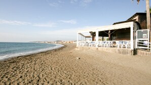 Un hotel sulla spiaggia con una zona salotto riparata e vista sull'oceano.