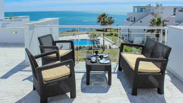 Un balcone con mobili in vimini, un tavolino e vista sull'oceano.