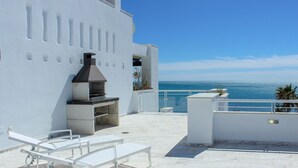 Una terrazza sul tetto con una griglia, posti a sedere e vista mare.
